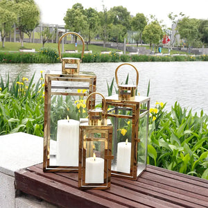 Set of 3 gold stainless steel decorative candle lanterns by JHY DESIGN with glass panels and loop handles.