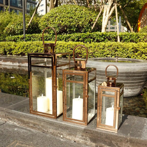 Set of 3 rose-gold stainless steel lanterns with glass panels and curved handles