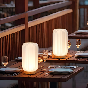 Rechargeable 9in cylindrical lamps; ribbed white shade with brass base, pair on dining table.