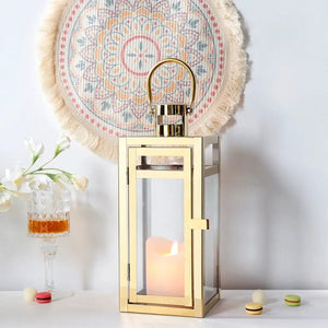 12'' high gold metal decorative candle lantern with glass panels and a curved top handle