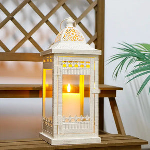 Decorative candle lantern, beige with gold brush accents, vintage metal frame with glass panels and a lit candle.