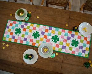 Shamrocks Rainbow Table Runner quilt kit by Block Party Quilt Co; rainbow patchwork with green shamrocks.