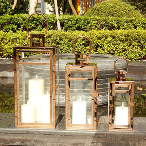 Set of 3 rose-gold stainless steel decorative candle lanterns with glass panels and curved handles