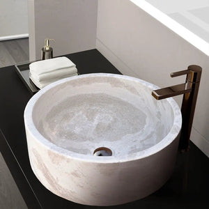Natural stone white limestone vessel sink, polished interior, 16in dia x 6in high, bronze faucet on black countertop