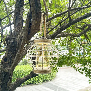 White metal cage battery-powered LED lantern hanging from jute rope