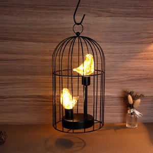 12-inch tall battery-operated birdcage lamp with warm amber bird-shaped LEDs inside a black metal cage