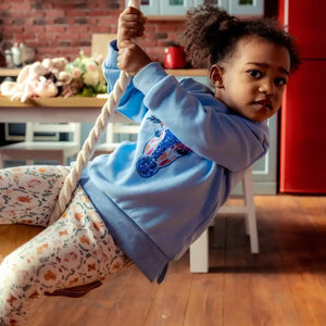 Wooden rope swing for kids, single indoor swing with thick rope, child in blue hoodie.