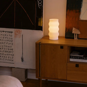 Wub Table Lamp with white ribbed glass body on a wooden nightstand, warm ambient light