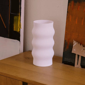 Wub Table Lamp; white ribbed ceramic body with cloud-inspired curves on a wood surface.