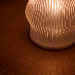 Yuji Table Lamp by Terra Labs with a ribbed warm-amber shade.