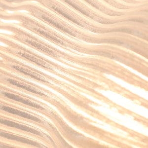 Yuji table lamp by Terra Labs, peach-gold brushed metal finish with wave-like ridges.