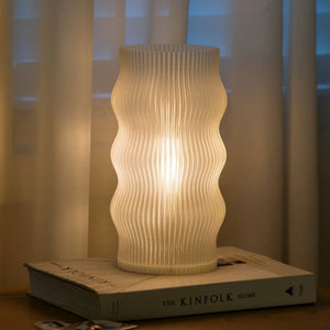 Yuji table lamp with a white ribbed ceramic body resting on a Kinfolk book.