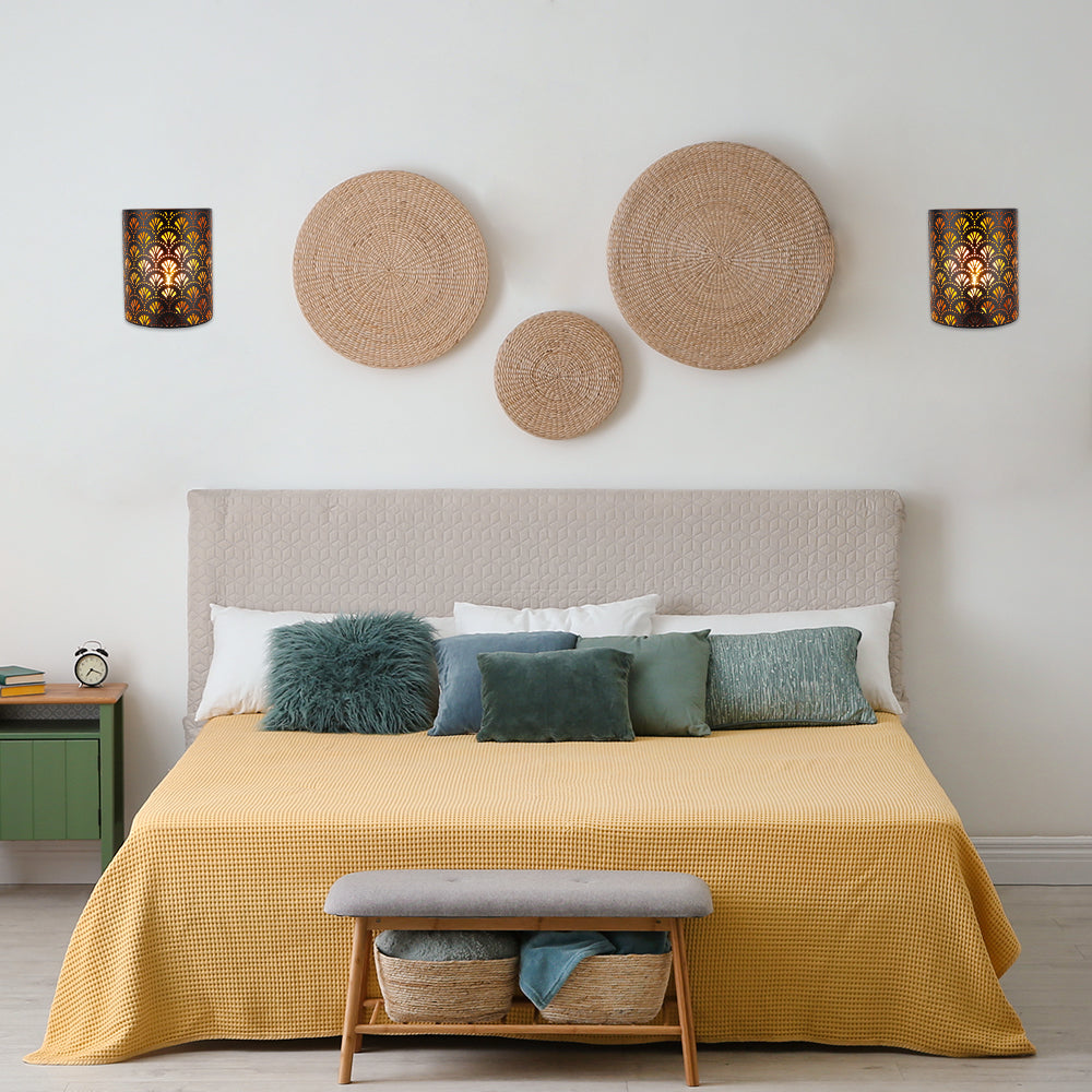 Cozy bedroom interior with a neatly made bed, yellow bedspread, decorative pillows, woven wall décor, bedside table, and bench at the foot of the bed.