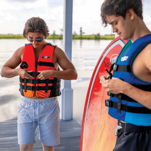 WOW Watersports Vis-Wave adult life vests; blue vest on the right and red/orange vest on the left by the water.
