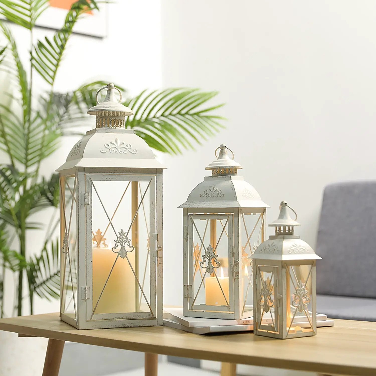 Decorative metal lanterns set of 3 by JHY DESIGN, distressed white finish with candlelight on a wooden table.