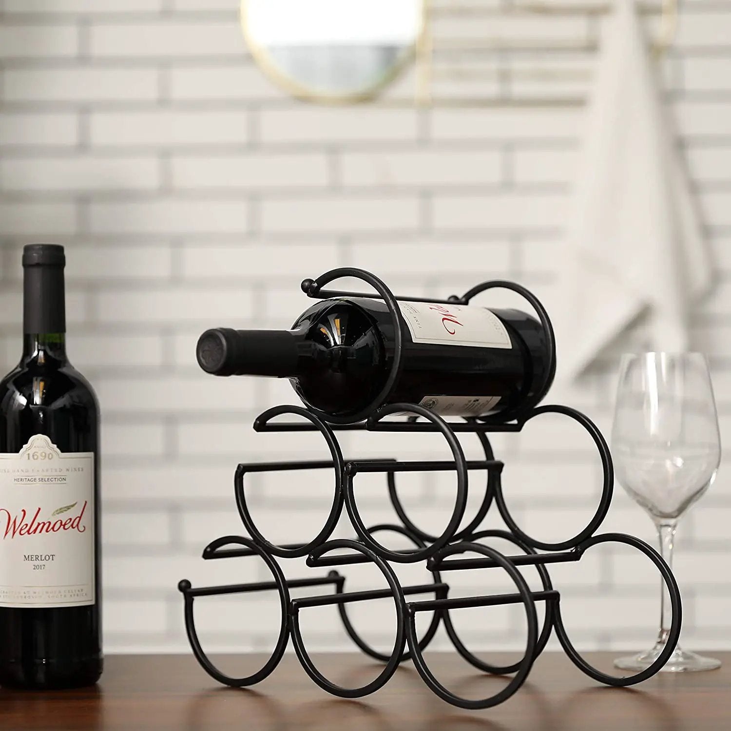 Iron tabletop wine rack, black metal; two wine bottles and a glass visible nearby.