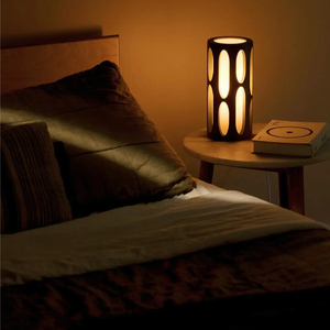 Amoeba Table Lamp by Terra Labs, black cylindrical lamp with oval cutouts on a bedside table.