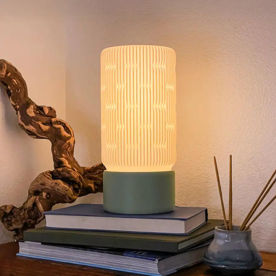 Liunk Table Lamp with ribbed white shade and teal base on a stack of books
