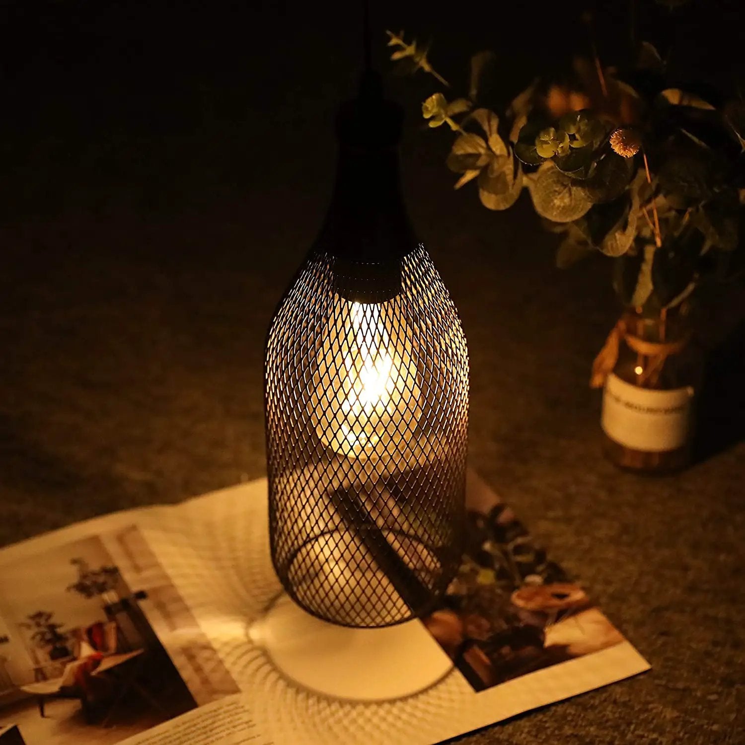 Battery-powered hanging lamp with black metal mesh cage and warm glow.