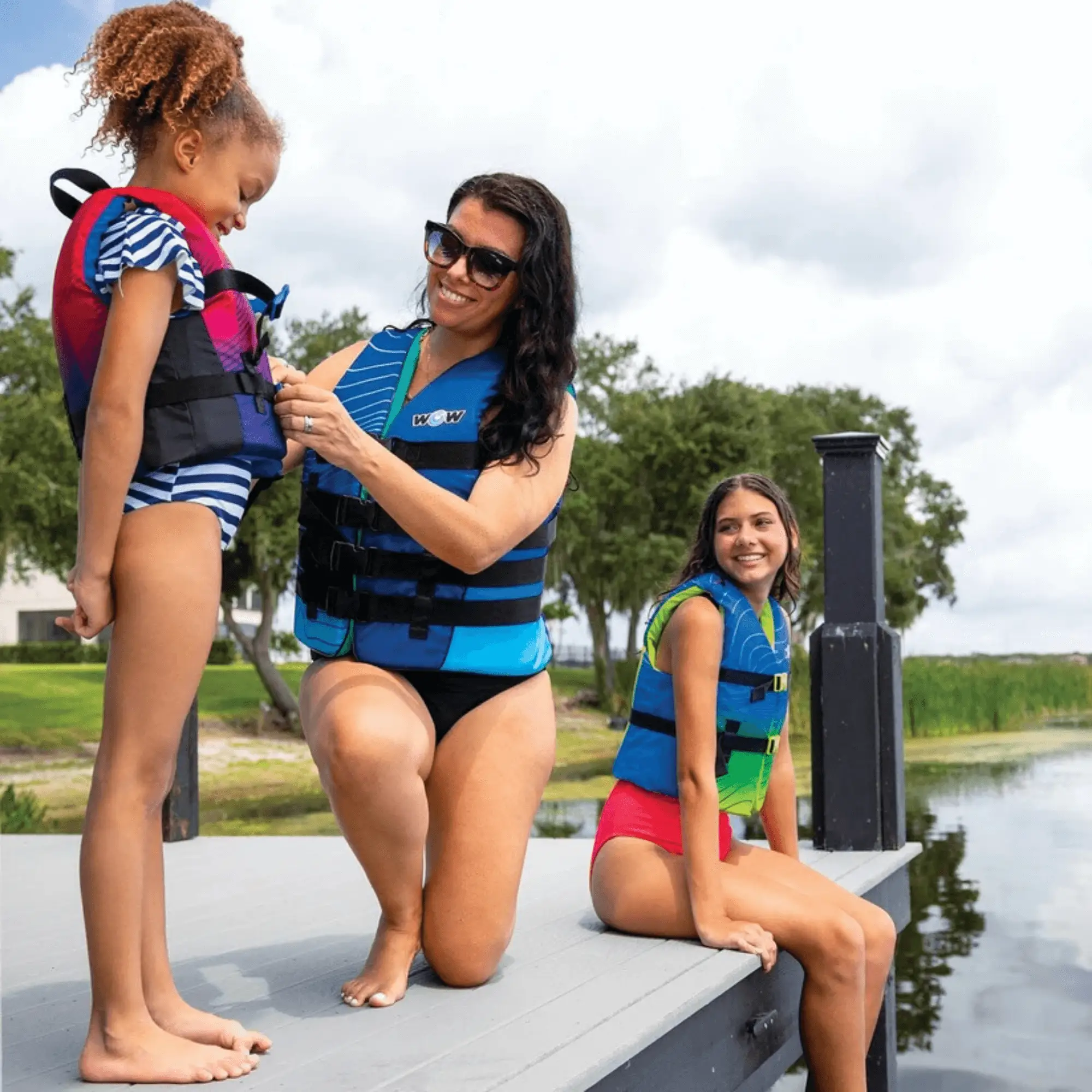 WOW Watersports Vis-Wave adult life vest blue on three people on a dock