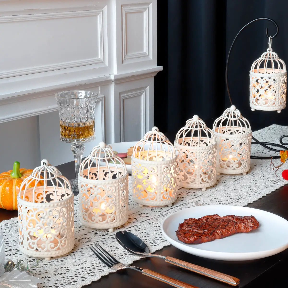 6-pack small white metal candle lanterns with intricate lattice and warm candlelight on a dining table