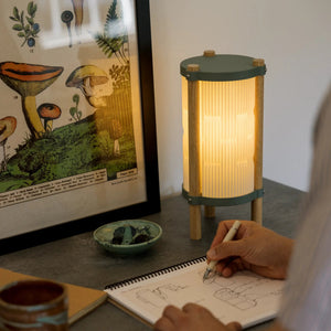 Toro Table Lamp by Terra Labs; green top and bottom bands, wooden legs, ribbed shade.