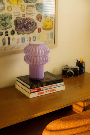 Oppi table lamp, purple ribbed ceramic base on a stack of design books