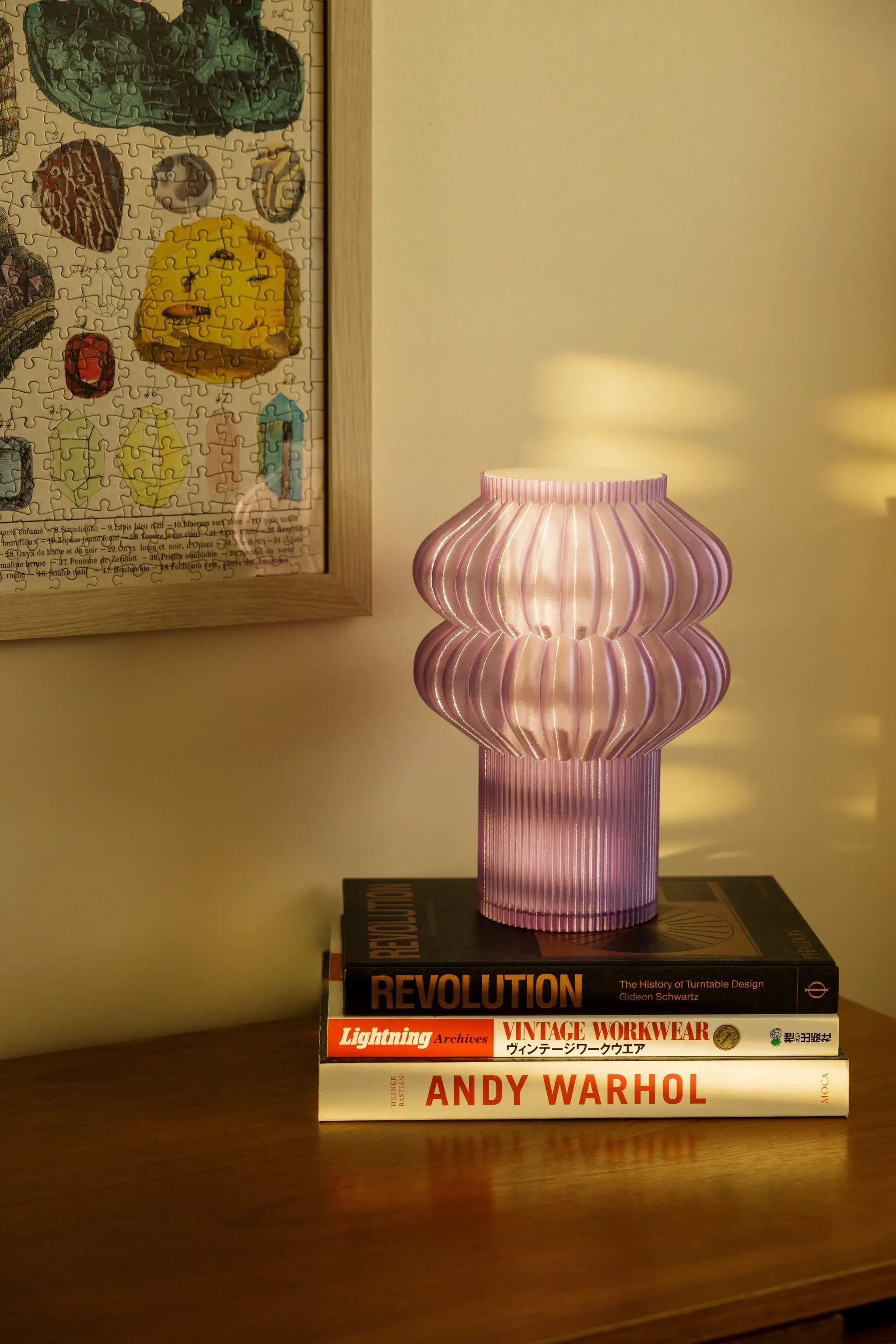 Oppi table lamp by Terra Labs; pink ribbed glass with sculpted, rounded form on a stack of design books.