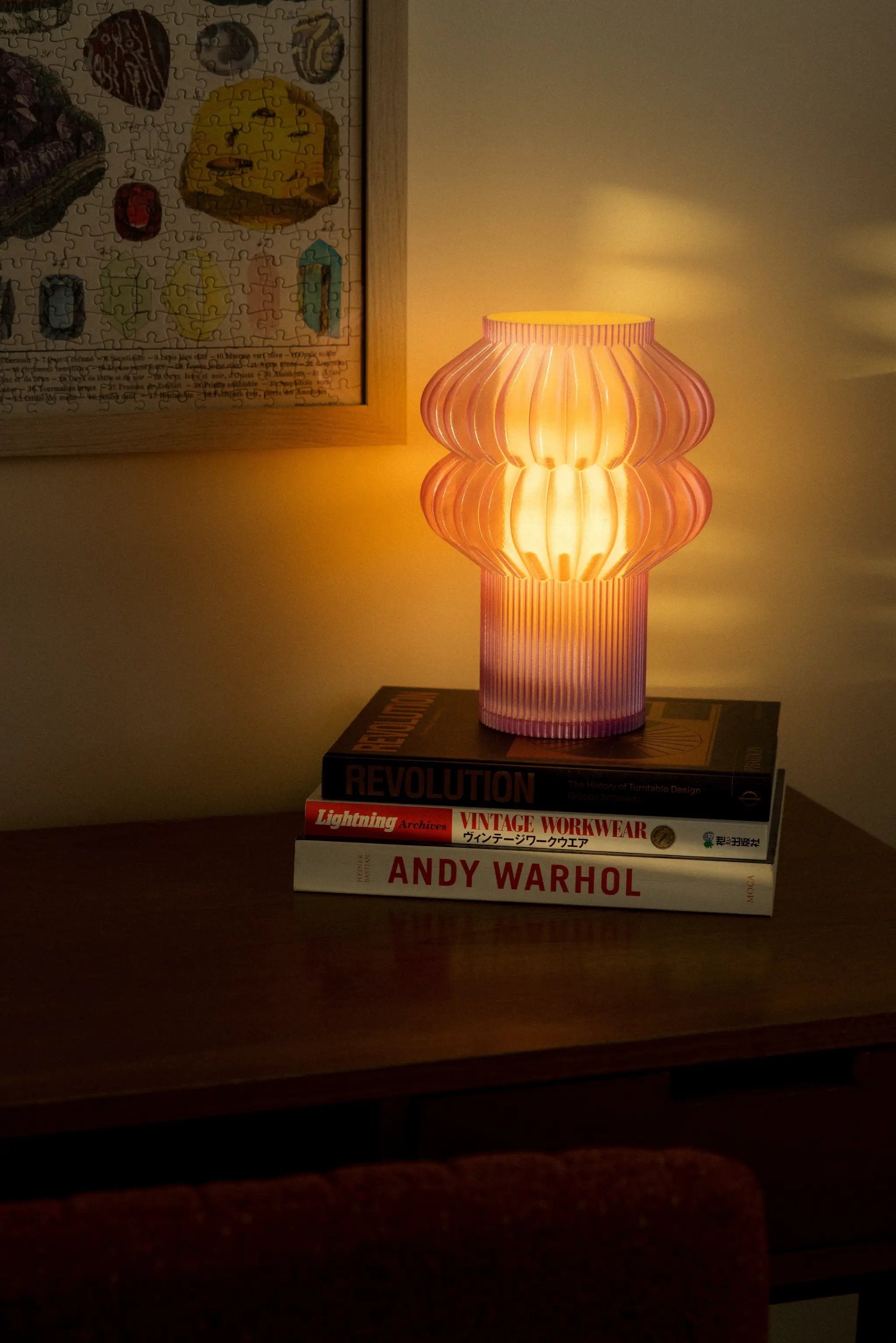 Oppi Table Lamp by Terra Labs; pink ribbed glass lamp on a stack of design books.