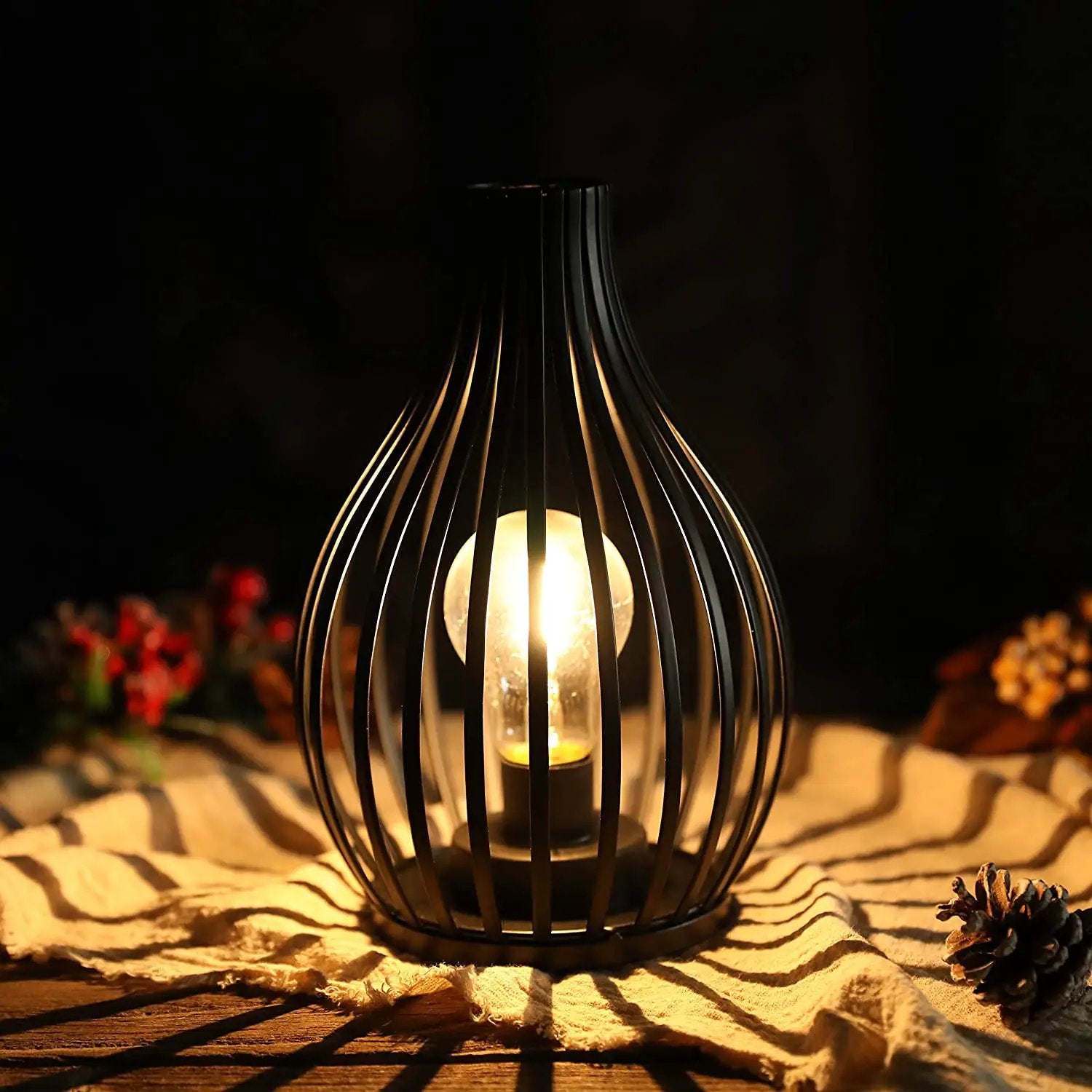 9.5-inch high battery-powered table lamp with a black metal cage and warm glow