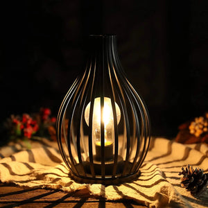 9.5-inch high battery-powered table lamp with a black metal cage and warm glow