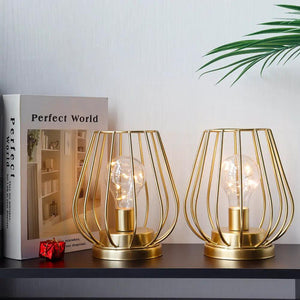 7-inch tall gold metal cage cordless table lanterns set of 2 with glass bulbs.