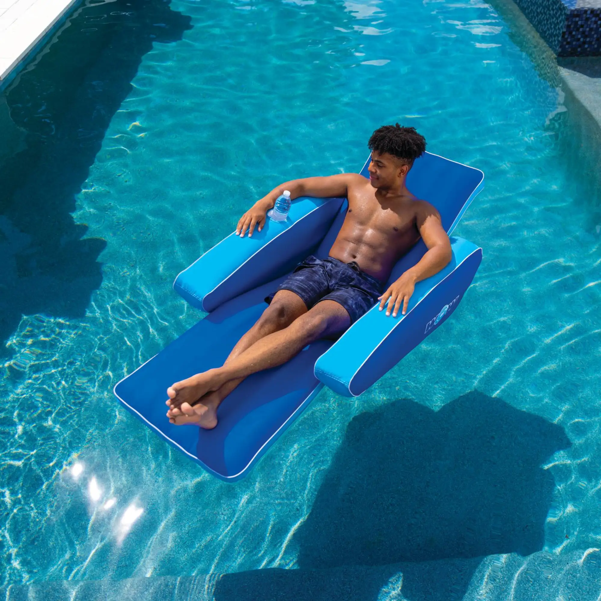 WOW Watersports Modern Lounger pool float in blue with cupholder, person relaxing in pool.