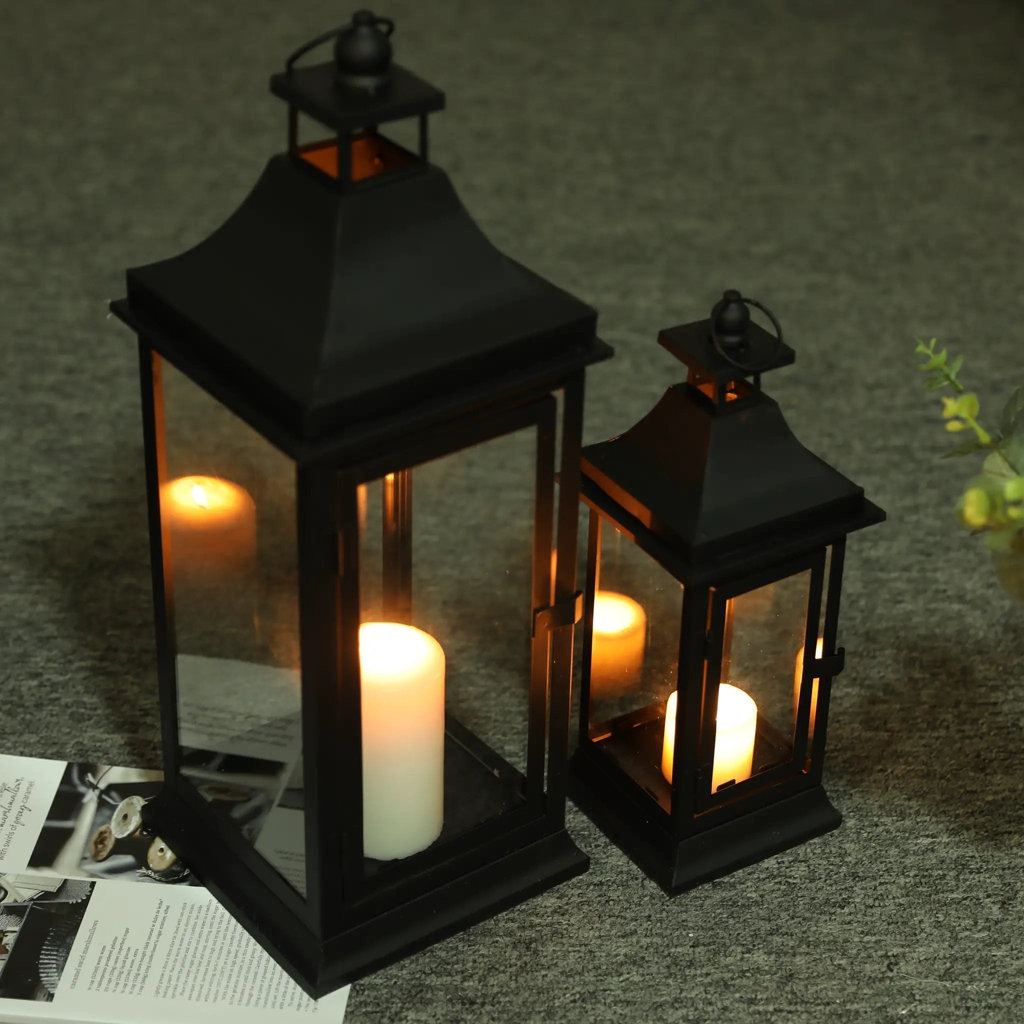 Decorative candle lanterns set of 2 by JHY DESIGN, black metal with glass panels and lit candles.