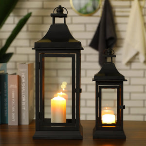 Set of 2 black outdoor candle lanterns, 13 and 19.5 inches tall, with glass panels and warm glowing candles.