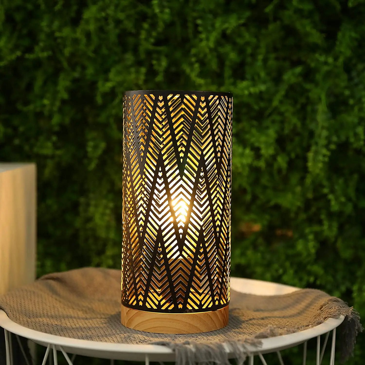 11-inch battery-powered metal lamp, black with geometric chevron cutouts, warm glow on wooden base