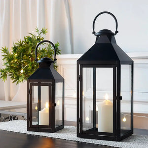 Set of 2 black metal candle lanterns with glass panels, 17.5in and 13.5in tall.
