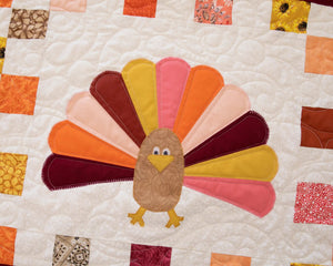 Turkey Quilted Table Runner Pattern by Block Party Quilt Co; colorful turkey applique on beige quilt with patchwork