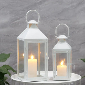 Set of two white metal decorative candle lanterns with glass panes and handles, sized 17.5 and 13.5 inches.
