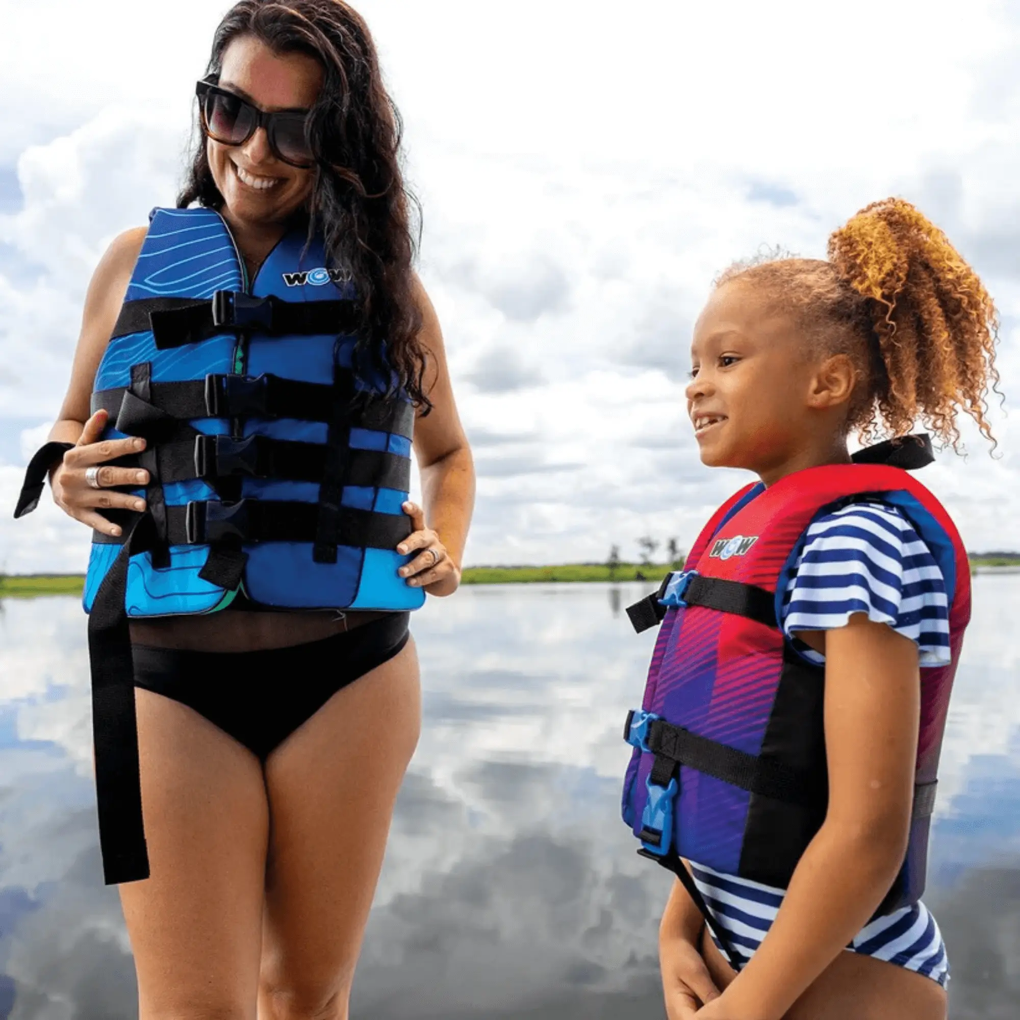 WOW Watersports Vis-Wave adult life vest blue with black straps; two people wear blue and red life vests.