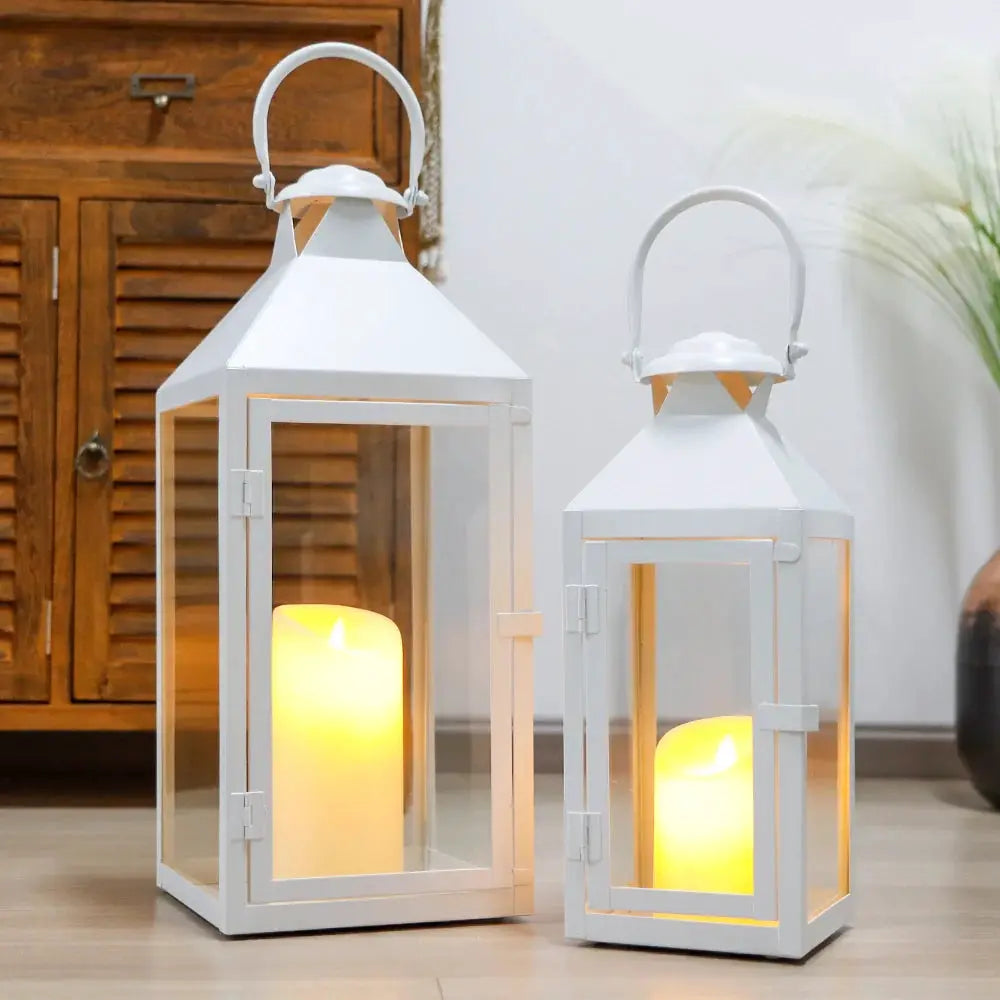 Set of 2 white metal decorative candle lanterns (17.5in and 13.5in) with glass panels and lit candles