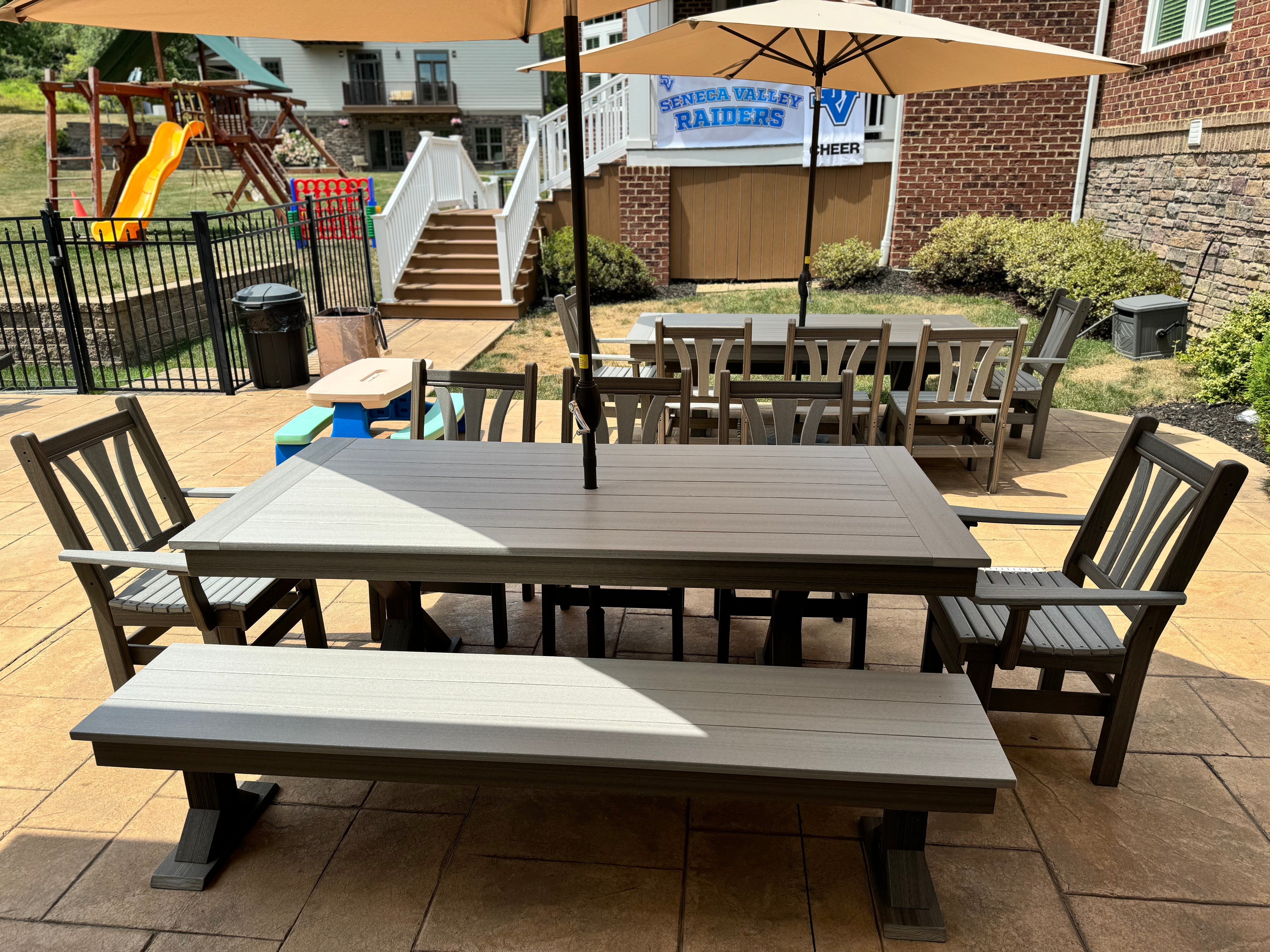 Trestle X outdoor bench by Wooden Whale Workshop; gray wood patio dining table with matching benches under umbrellas.