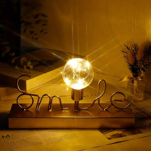 Decorative cordless lamp by JHY DESIGN featuring warm white fairy-light globe on a gold base with the word Smile