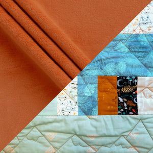 Bricks and Beams Quilt Kit Timberline by Block Party Quilt Co; orange fleece backdrop with blue patterned fabric strips.