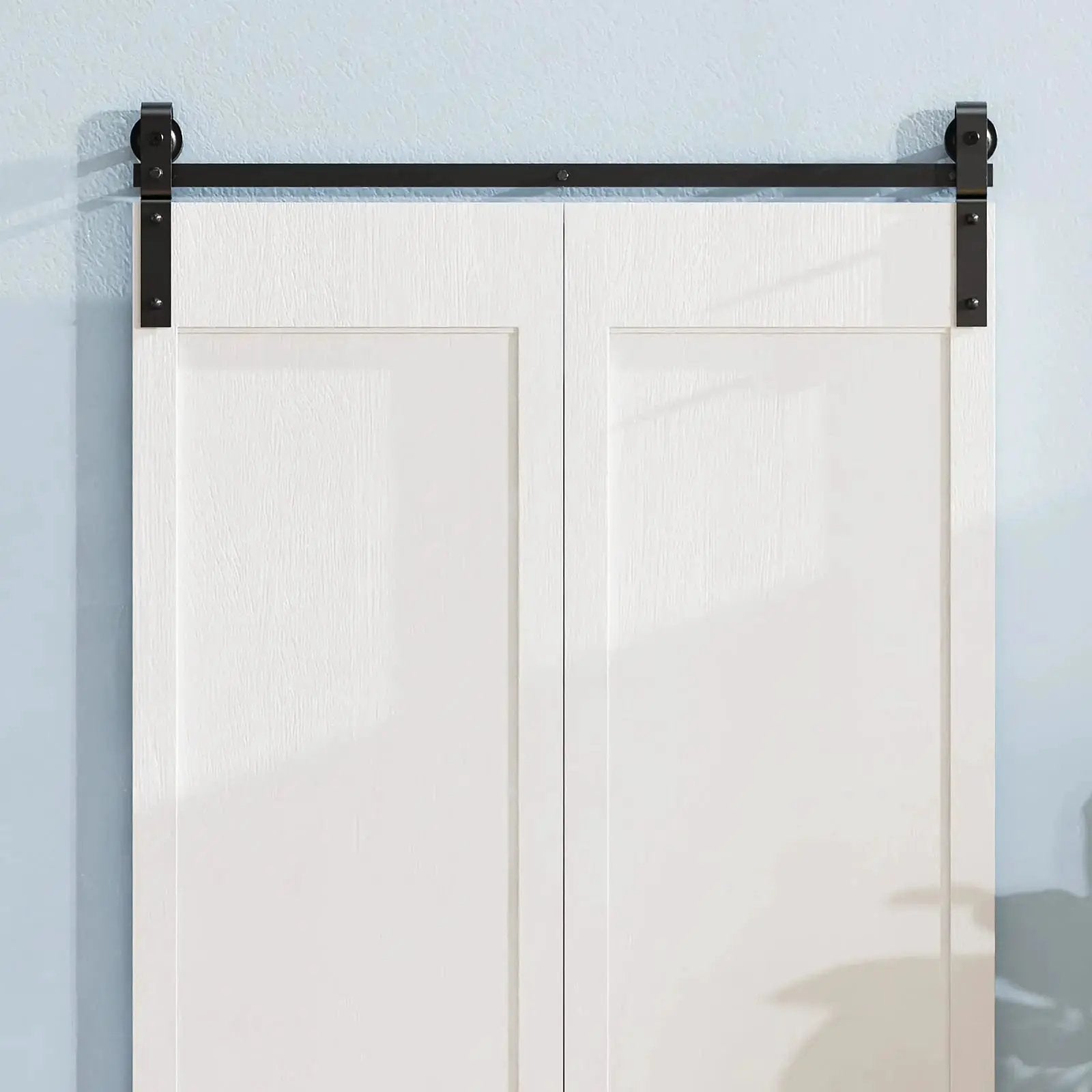 Bi-fold sliding barn door hardware track kit in black metal (no door) mounted above white double doors.