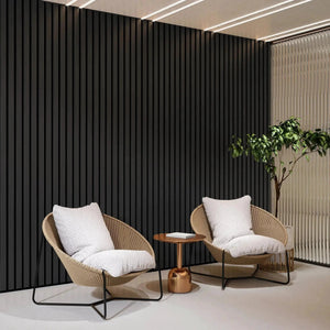 Solid Wood Acoustic Slat Wall Panels Broad Strip in black and beige with two wicker lounge chairs.