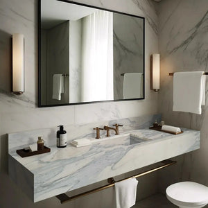 Calacatta Olivia marble wall-mount bathroom sink by Villohome with gold fixtures on a 60in-long vanity