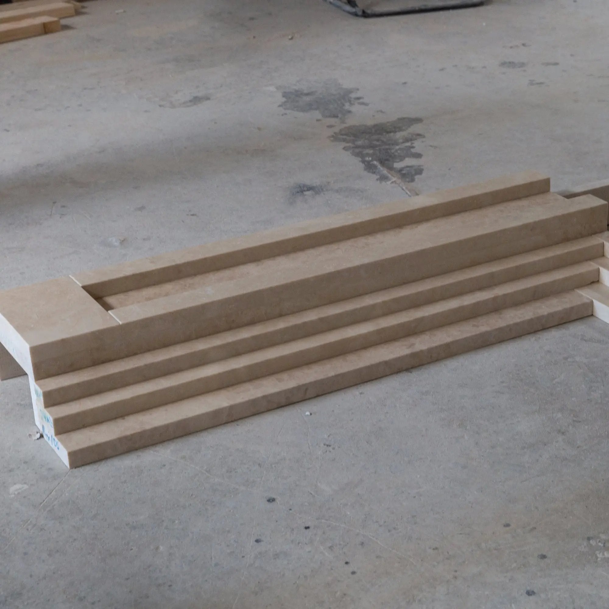Beige marble fireplace mantel pieces stacked on a concrete workshop floor.