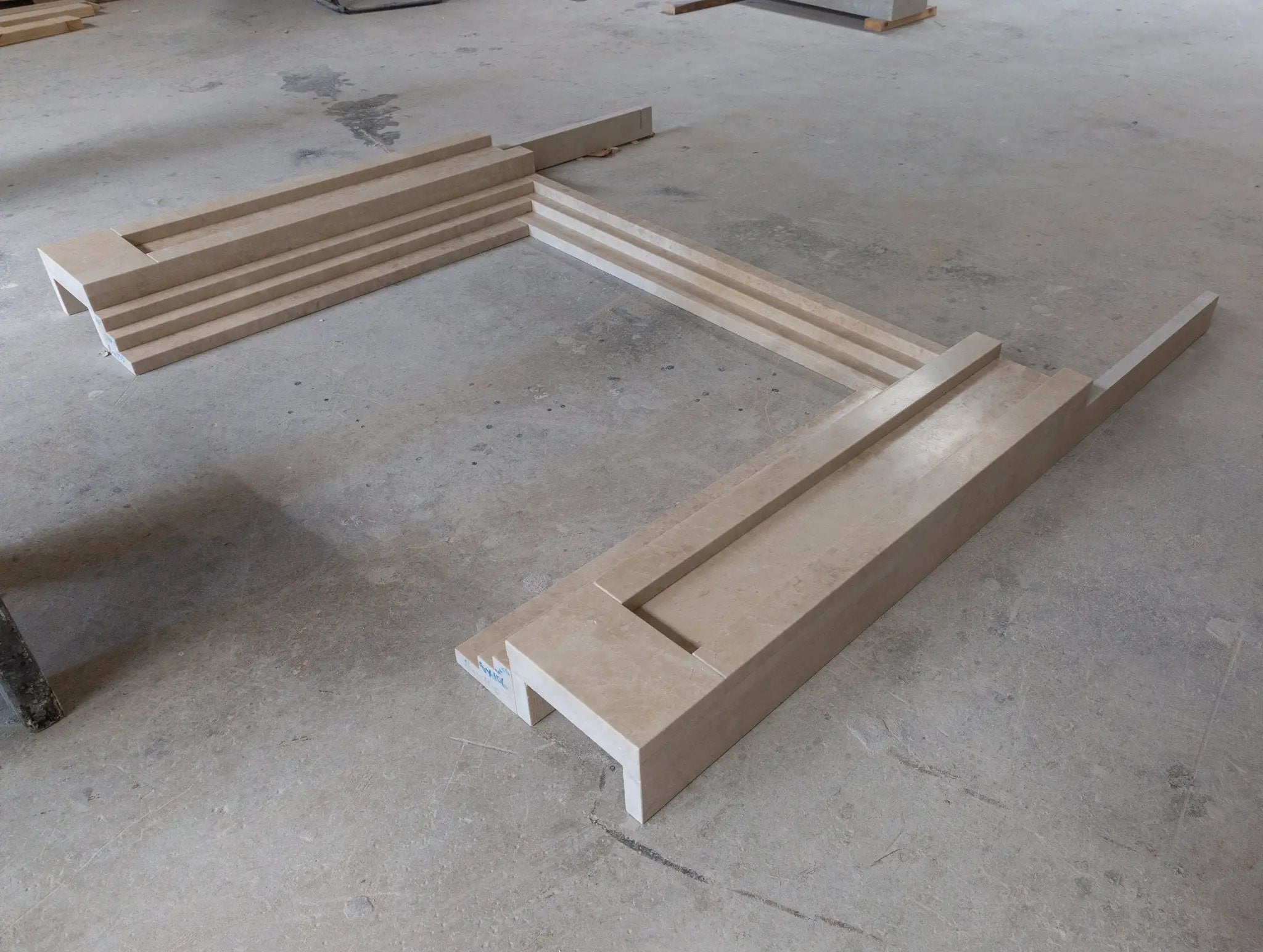 Cappuccino beige marble fireplace mantel components laid out in a workshop.