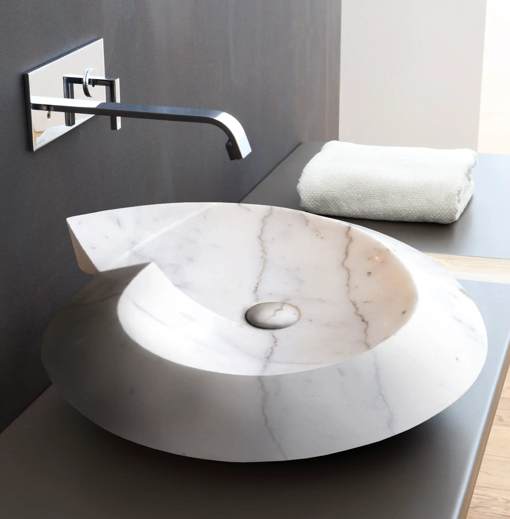 Carrara marble helix-shaped above-counter bathroom sink in polished white stone